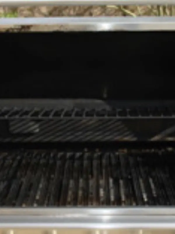 Built-in BBQ grill with greasy, carbon-covered grates before cleaning