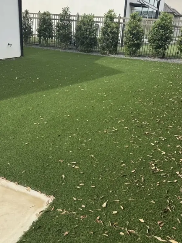 Artificial turf covered in leaves and debris before cleaning