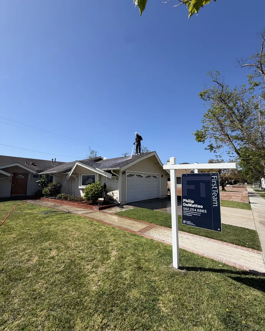 Titan crew member washing a roof with a for sale sign in the front yard